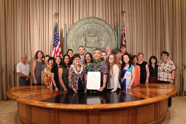 A photo of UHM LIS members and Governor David Ige with a plaque showing the proclamation of the "UH Mānoa Library and Information Science Program Week."