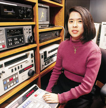 A young woman sits at control panel