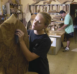 sculptor and woodcarver Cori Wilbanks carving a large slab of wood