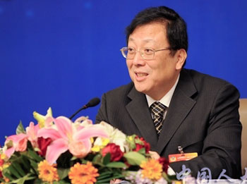 Hao Ping at table with floral arrangement and microphone