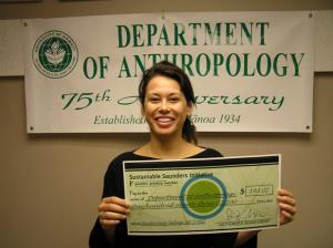 Marti Kerton holds a check from Sustainable Saunders
