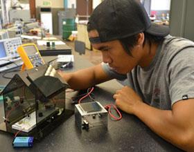 Electronics student Philip Daquep works on a solar battery charger built by Hawai'i CC students.