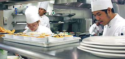 Culinary students preparing dishes in The Pearl restaurant kitchen