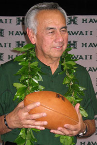 Norm Chow wearing maile lei and holding a football