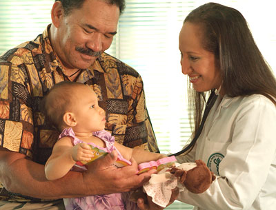 A medical student examining a baby held by a man