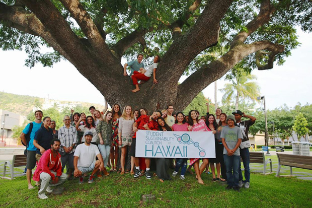 students holding a banner under a big tree