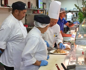 Jay Kido and classmate watch as instructor puts together a dish
