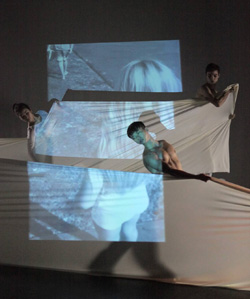 Dancers using white sheets to project images onto stage