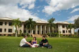Students sitting on the lawn in front of Hawaii Hall