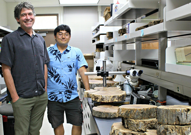 two people standing in lab next to a counter with tree trunk samples
