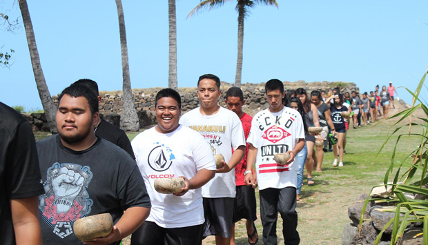 Students in a line walking down from Heiau, each with a bowl in their left hand
