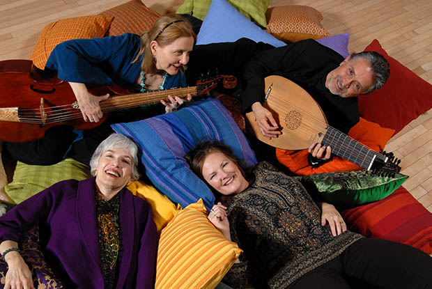 Four people lying on cushions. Two have string instruments.