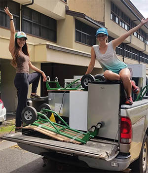 Two students posing on a truck with mini-fridges in the truck bed
