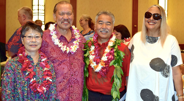 four people standing together wearing lei
