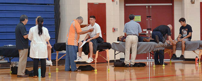 Medical professionals examining students in a gym