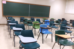 dated desk-chairs and green chalk boards in a classroom