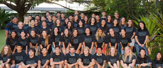 rows of posed smiling students wearing the same Shidler t-shirt