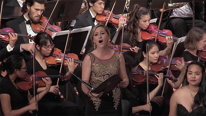 Caitlin Cavarrochi singing in front of an orchestra