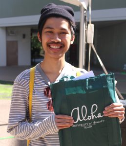 person holding UH Manoa informational bag