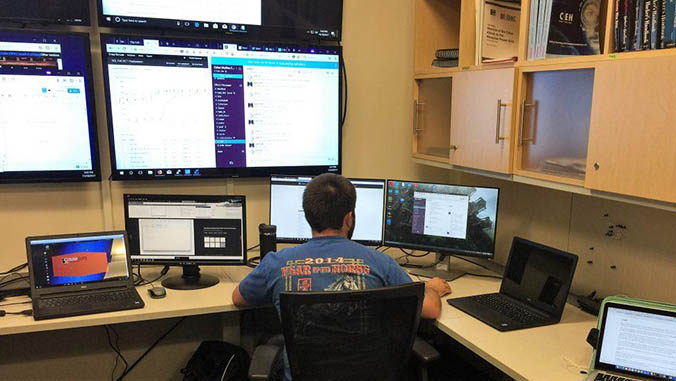 Student sitting in front of multiple computer screens