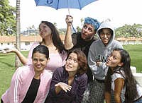 student crouching under an umbrella