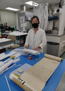 Liane Naʻauao, paper conservator, with miniature mockup of scroll carrier.