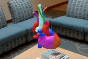 A  heart appears to float above a table in the lobby at JABSOM, through augmented reality.
