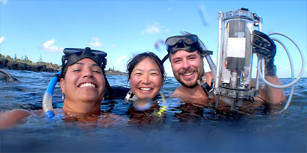Three people wearing snorkel gear in blue water