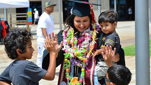 graduate in cap in gown with children