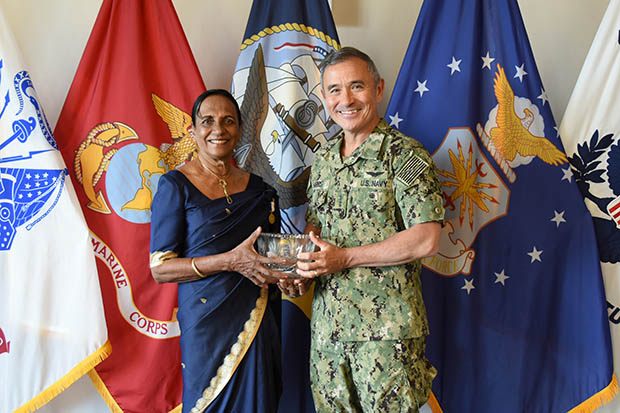 Cooray with Admiral Harris standing in front of flags