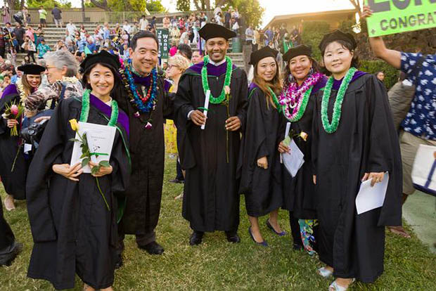 LLM graduates in regalia outside with lei