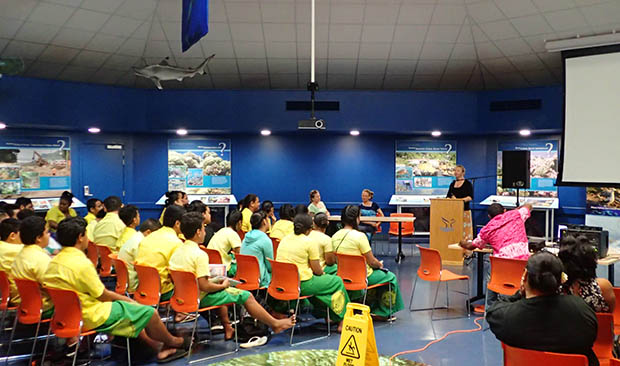 A room of seated students with a speaker at a podium