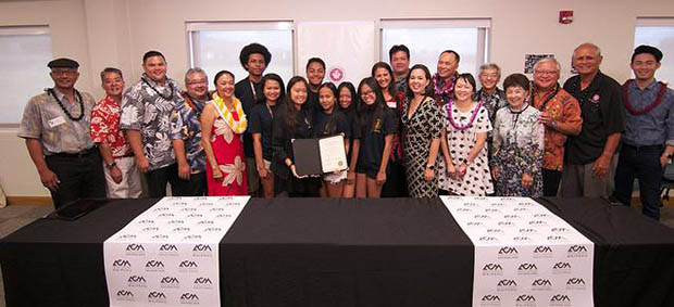 A group of people behind a table holding a signed document.