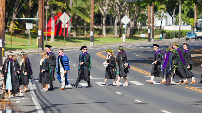 law school graduates in cap and gowns crossing street