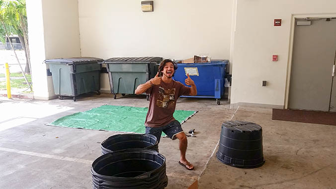 Student giving double thumbs up with trash containers