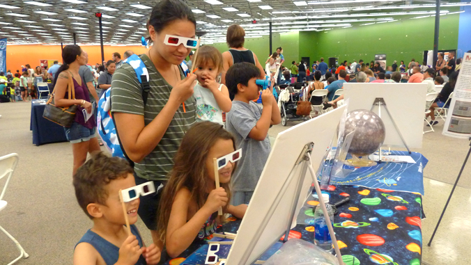 family using viewing glasses to look at exhibit