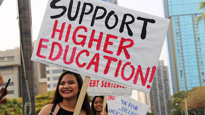 Rovy Dipaysa holding a sign to Support Higher Education
