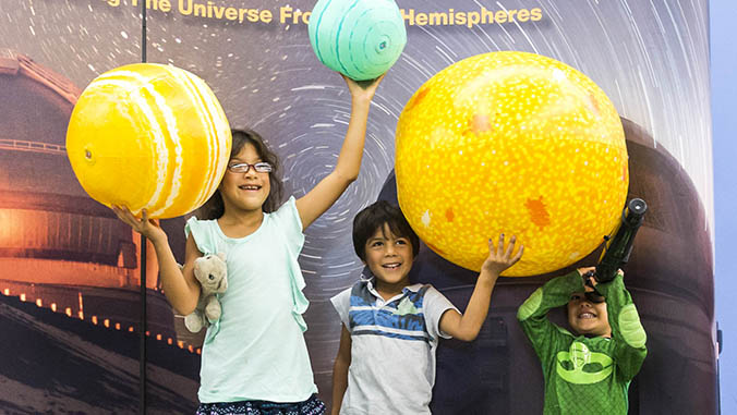 Kids holding up inflatable planets