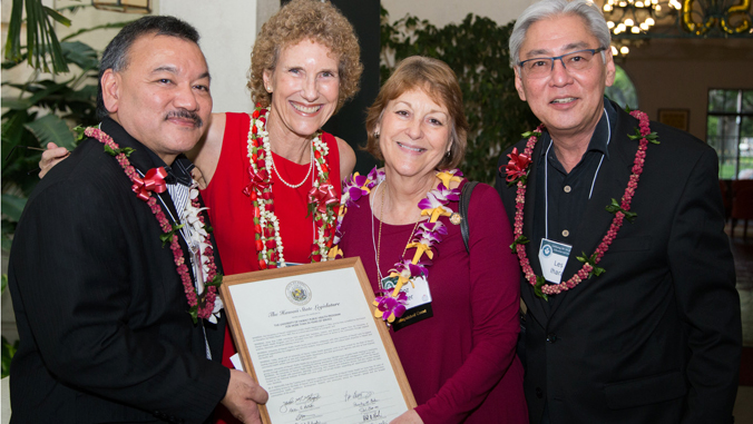 four people holding framed note