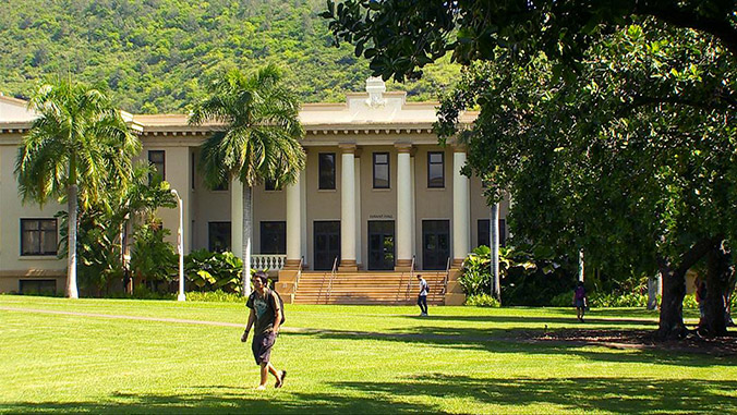 Student walking on the lawn in front of Hawaii Hall