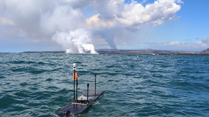 autonomous robots in the ocean with volcanic gas plumes in the background