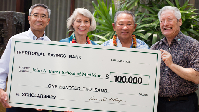 four people holding big check