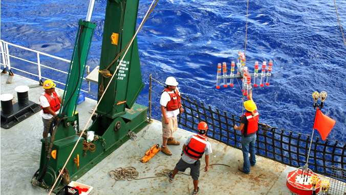 people collecting water samples from the deck of a ship