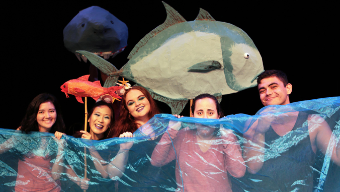 five people holding a plastic blue sheet