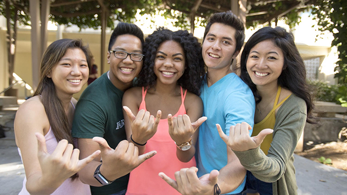 Smiling students flashing shaka