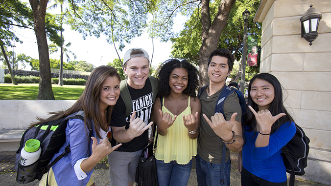 Smiling students flashing shaka