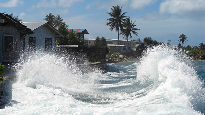 waves crashing against shoreline by houses