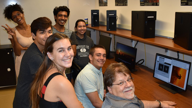teacher and students gather around new computers