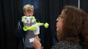 teacher and student blowing on two anemometer designs