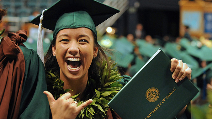 Smiling woman holding diploma and flashing a shaka